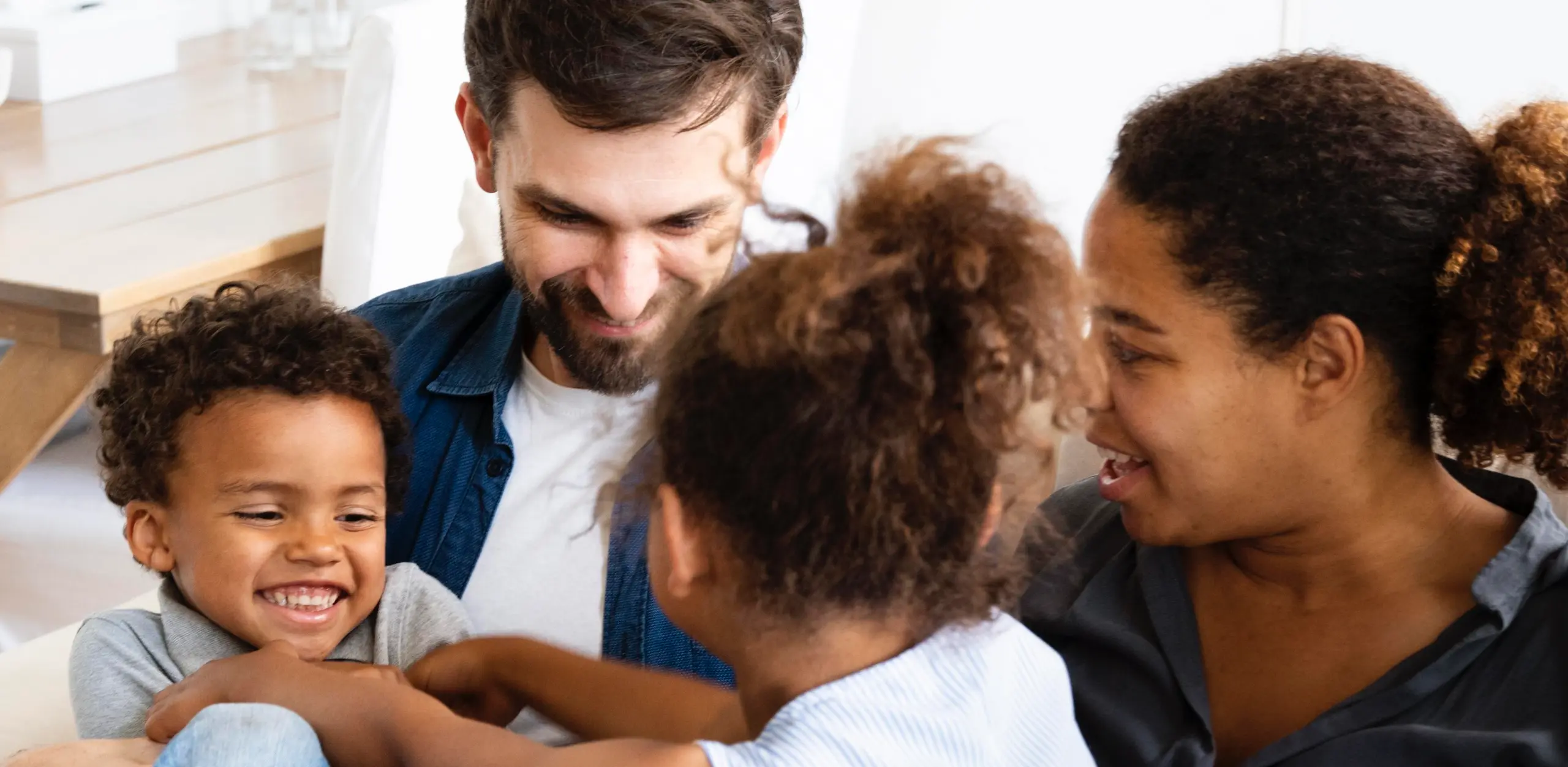 Eine Familie die einander zugewandt ist und gemeinsam lacht.